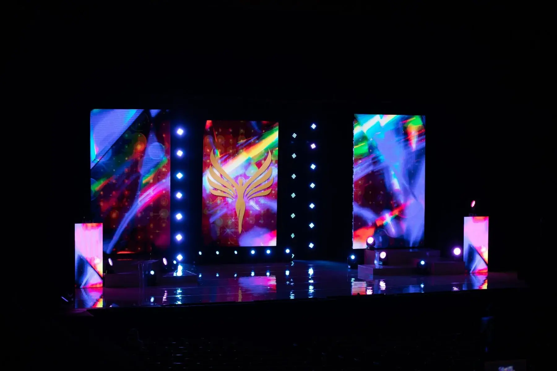 Wide multi-screen stage filled with vivid video content and purple-blue light